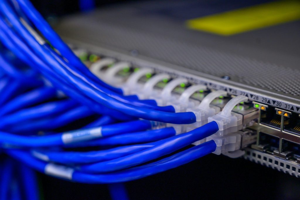 Detailansicht von blauen Ethernet-Kabeln, die an einen Netzwerk-Switch in einem Rechenzentrum angeschlossen sind.